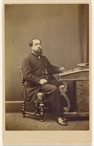Unidentified bearded man seated at writing desk, in 3/4 profile