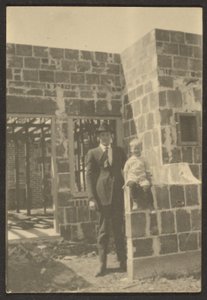 Man Standing with Child in House Under Construction by Louis Fleckenstein