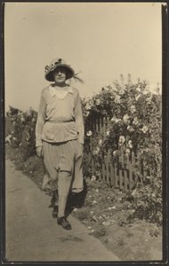 Woman Walking Along Fence with Flowers