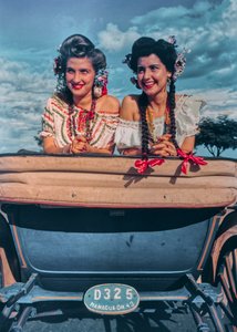 Young Nicaraguan women pose in festive costumes and headgear in back of a carriage