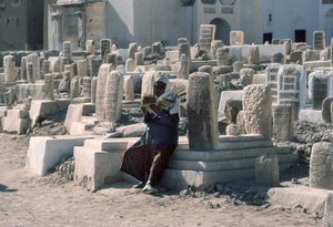 Yemenite man recites the Koran in cemetery with tombs at Sayun, Hadramawt, South Yemen