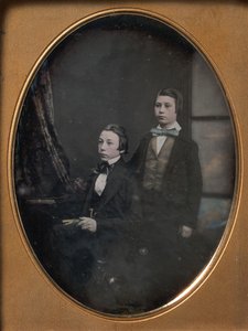 Two Young Men in Bow Ties, One Seated Holding a Book, One Standing