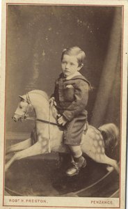 Young boy sitting on a rocking horse by Robert H. Preston