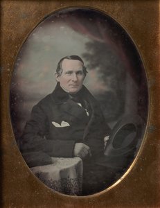 Man Wearing Coat and Gloves, Holding Hat, Seated in Front of Painted Outdoor Backdrop, 1840s by Samuel Broadbent Jr..