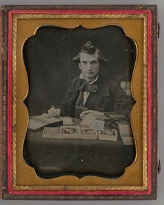 Untitled Portrait of Seated Man Holding a Daguerreotype and Brush by Samuel J. Miller