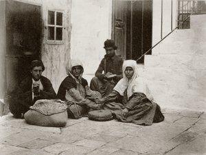 Women grinding flour with round millstones within a courtyard of a house in Jerusalem