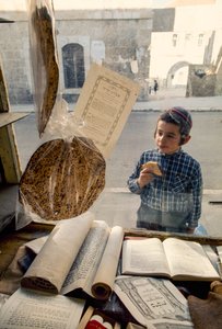 Conservative Jewish boy eating cake peers into a religious bookstore by Ted Spiegel