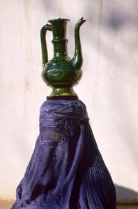 Woman in Kabul secluded from view by silk chadri carries jug by Thomas J. Abercrombie