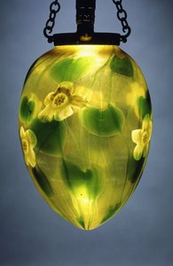 A hanging lantern, decorated with green leaves and vines and yellow iridescent flowers