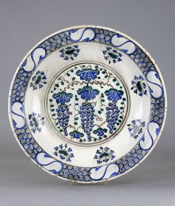 An Iznik pottery dish with a central roundel depicting three bunches of grapes and vine leaves, c.1570 by Turkish School