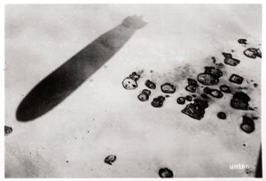 Aerial view of a desert settlement, with a shadow cast by a Zeppelin