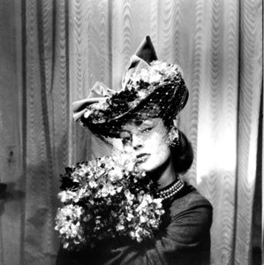Woman wearing a hat with a veil, holding a bouquet of flowers, Paris