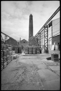 A general view of the Elswick Shot Tower, demolished 1968-69, used for creating lead shots, with a yard with palettes in the foreground, c.1955-69 by Unbekannter Künstler