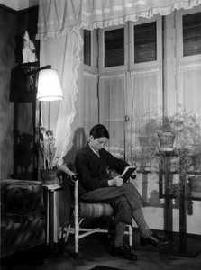A teenager sitting in a bourgeois interior reads a book, 1915