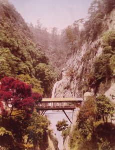 Covered bridge in a steep gorge, with waterfalls in the background, Japan, c.1890-1910