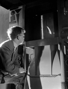 Engineer in wind tunnel with smoke tests under way on a small wing section