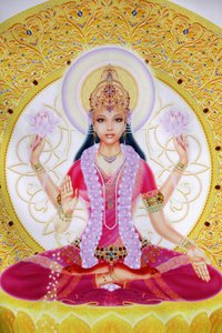 Picture showing Lakshmi, Goddess of wealth and consort of Lord Vishnu, sitting holding lotus flowers