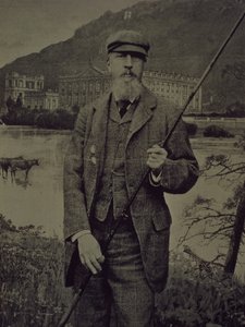Studio portrait of 8th Duke of Devonshire in tweeds holding fishing rod in front of a printed screen depicting Chatsworth by William M. Timlin