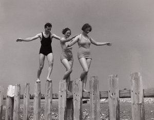 Two women and a man walking along a groyne, c 1930s
