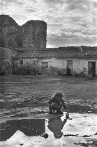 Young girl playing with a paper boat in a puddle surrounded by mud, Venosa, Basilicata, Italy by Unbekannt