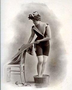 Young woman in a swimsuit taking a foot bath, around 1900