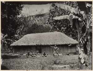 Man Posed in Front of Hut