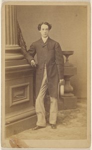 Unidentified man wearing gloves, holding a straw hat in his left hand, standing
