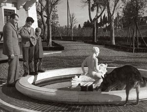 Gino Bartali with two kids and a dog near a fountain by Unknown photographer