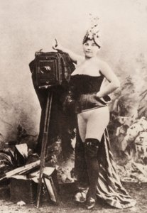 Portrait of a partially nude woman leaning on an antique camera by Unknown photographer