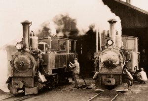 Two steam locomotives being maintained by two workers by Unknown photographer