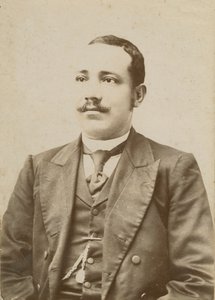 Photograph of a man wearing a dark colored suit with a pocket watch in his vest