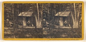 Family Posed in Front of Their Log Cabin in the Woods
