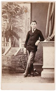 Studio portrait of young man in front of painted background of stairs and garden by William Bentley