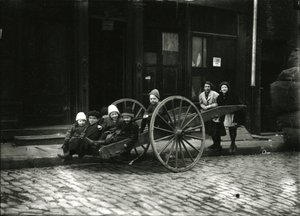 Group of children in cart, with girl and woman standing behind