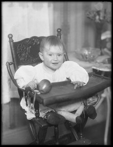 Unidentified infant seated in a high chair, 1915-16