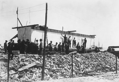 Several men around an enormous block of marble already squared off, just transported to the valley from the quarries in the Apuan Alps by A. Corsini