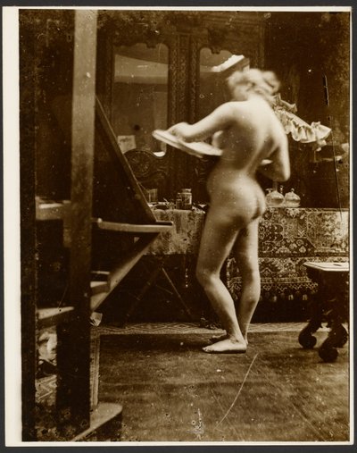 Female Nude Model Standing in Studio Holding a Sketchbook by Alphonse Maria Mucha
