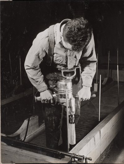 Man uses a handheld machine to work with a piece of wood by Arnold Eagle