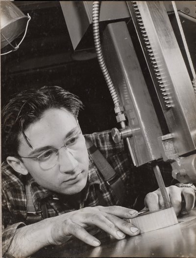 Man wearing glasses working with an industrial file by Arnold Eagle