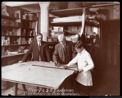Portrait of Henry and S.G. Lindeman with their son or grandson standing over shop drawings for a piano, 1910 by Byron Company