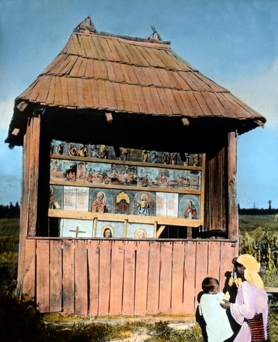 Mother with child in front of a little chapel with pictures of the Saints, Bukovina, Romania, circa 1920 by Carl Simon