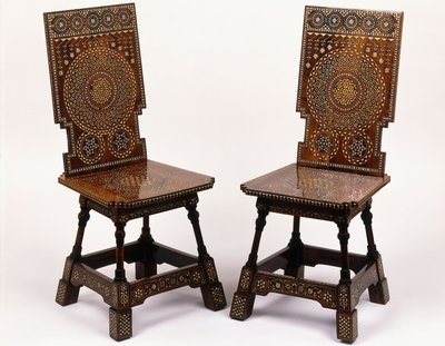 A pair of mahogany chairs with pewter and ivory inlaid floral decoration by Carlo Bugatti