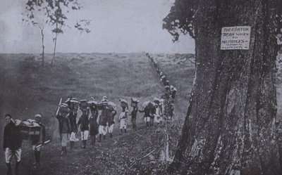 Line of men carrying goods from the equator to Selfridges, London by English Photographer