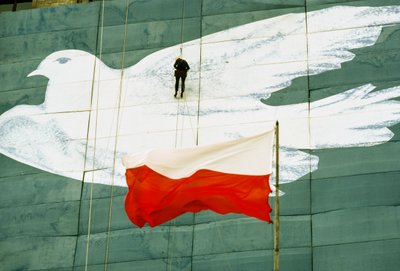 A worker puts the finishing touches on a large banner of a peace dove. Palace of Culture by James L Stanfield