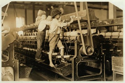 Small boys climbing on spinning frame to mend broken threads and replace empty bobbins at Bibb Mill, Macon, Georgia, 1909 by Lewis Wickes Hine