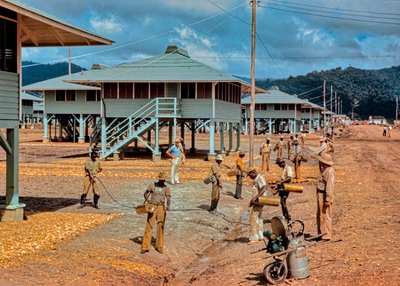 Men spray DDT pesticide insecticide to control insects around newly constructed barracks by Luis Marden