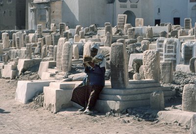 Yemenite man recites the Koran in cemetery with tombs at Sayun, Hadramawt, South Yemen by Lynn Abercrombie