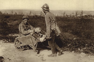 Captured French soldier transporting his wounded comrade in a wheelbarrow, World War I by Photographer German