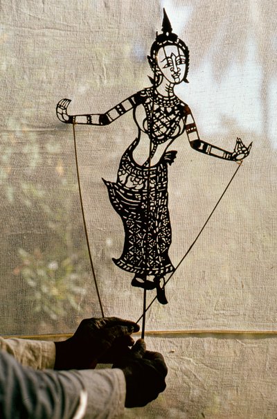 Puppeteer Manipulates Storytelling Shadow Puppet Against a Scrim for a Shadow Play by Thomas J. Abercrombie
