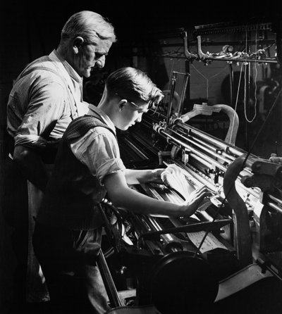 A master trains a young apprentice in machine knitting, Lyle and Scott, Hawick by Unbekannt